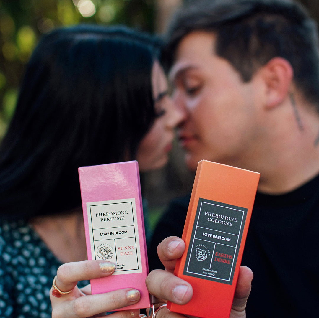 A couple in soft focus, about to kiss, holding Eye of Love's Bloom Sunny Daze pheromone perfume and Earth's Desire pheromone cologne.