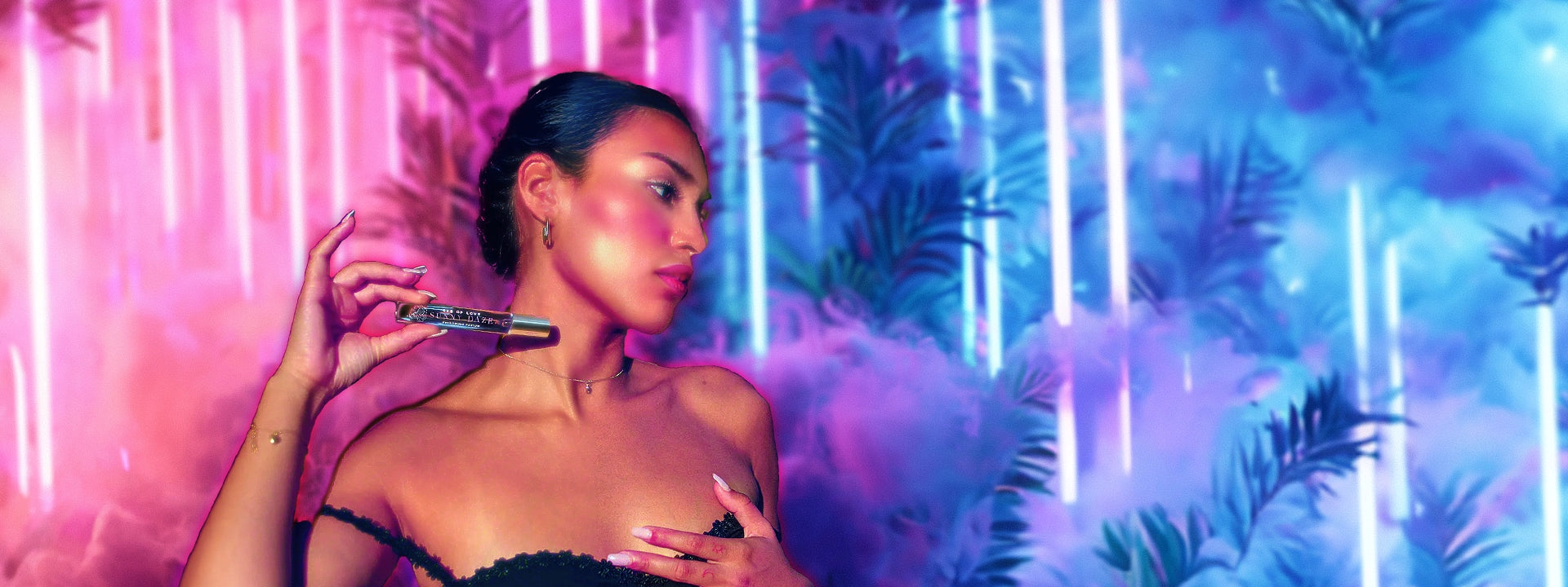 Sultry female in a black strap dress holding a bottle of Eye of Love's travel-sized Sunny Daze pheromone perfume, with a hazy neon pink and purple background